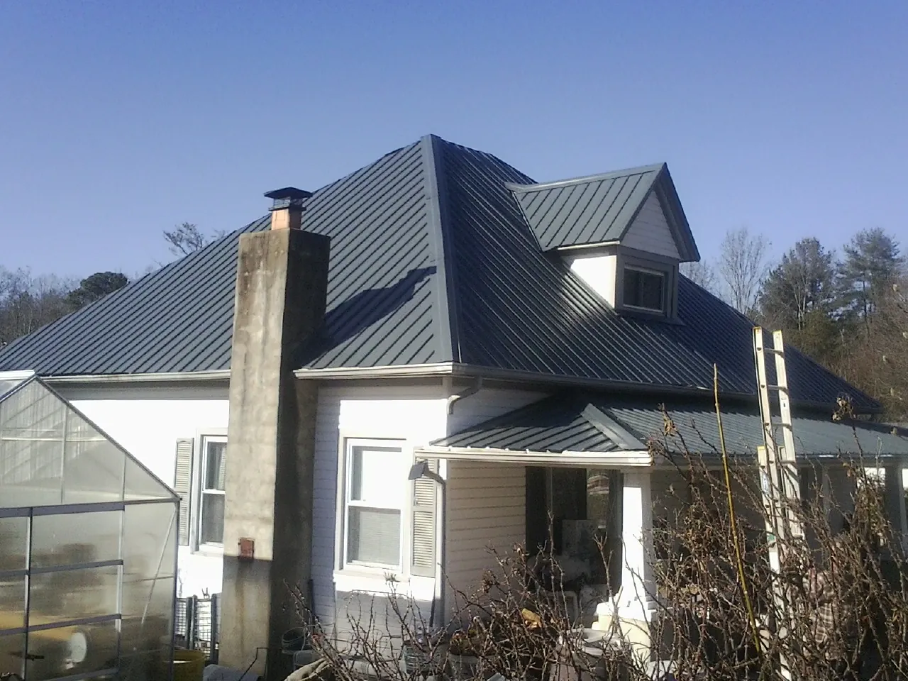 Dark blue standing seam metal roof on a white farmhouse with dormer — Slate & Tile Roof Repair by Roofing Brothers in Lake Hopatcong