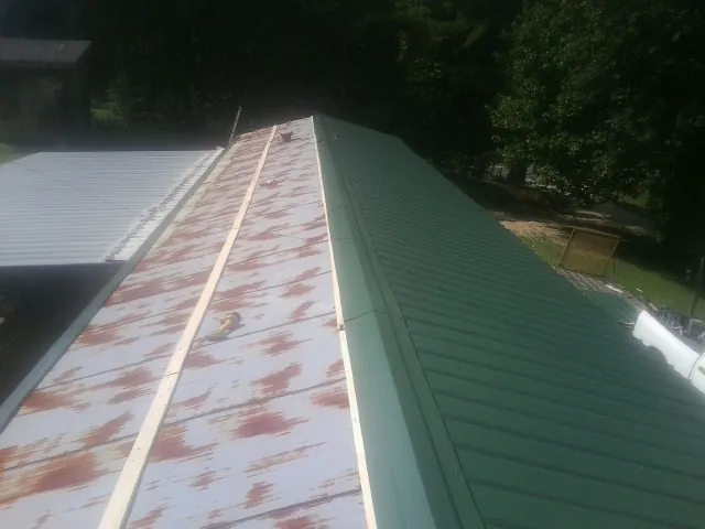 Old rusted panels beside newly installed green metal roofing — Wind Damage Roof Repair by Roofing Brothers in Lake Hopatcong