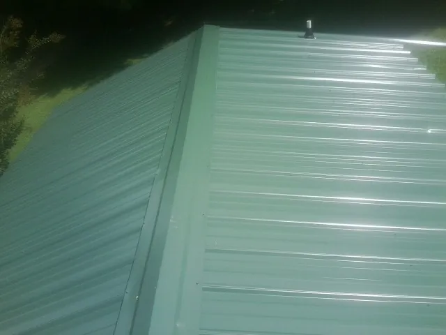 New green metal panels meeting at the ridge of a roof — Flat Roof Repair work by our crew in Lake Hopatcong