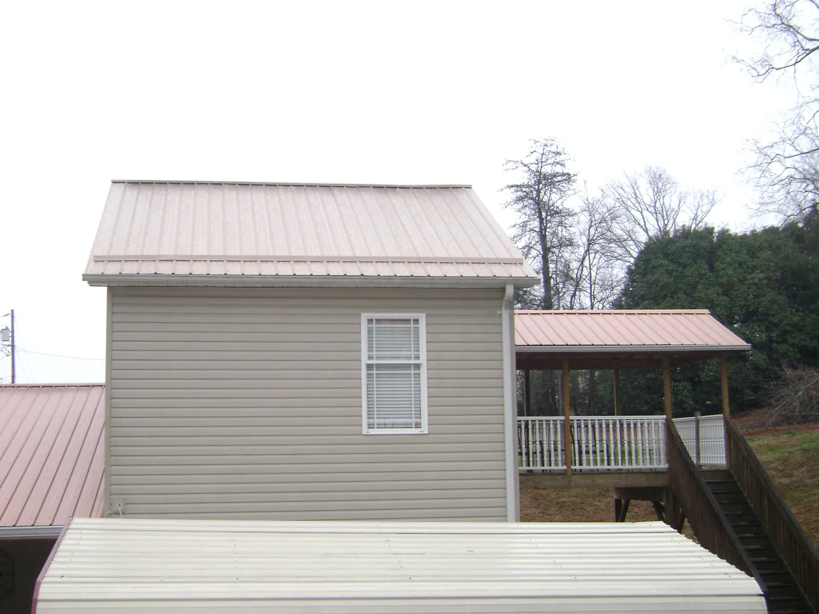 Tan metal roofs on a two story addition and attached porch, from a Roof Replacement job in Lake Hopatcong