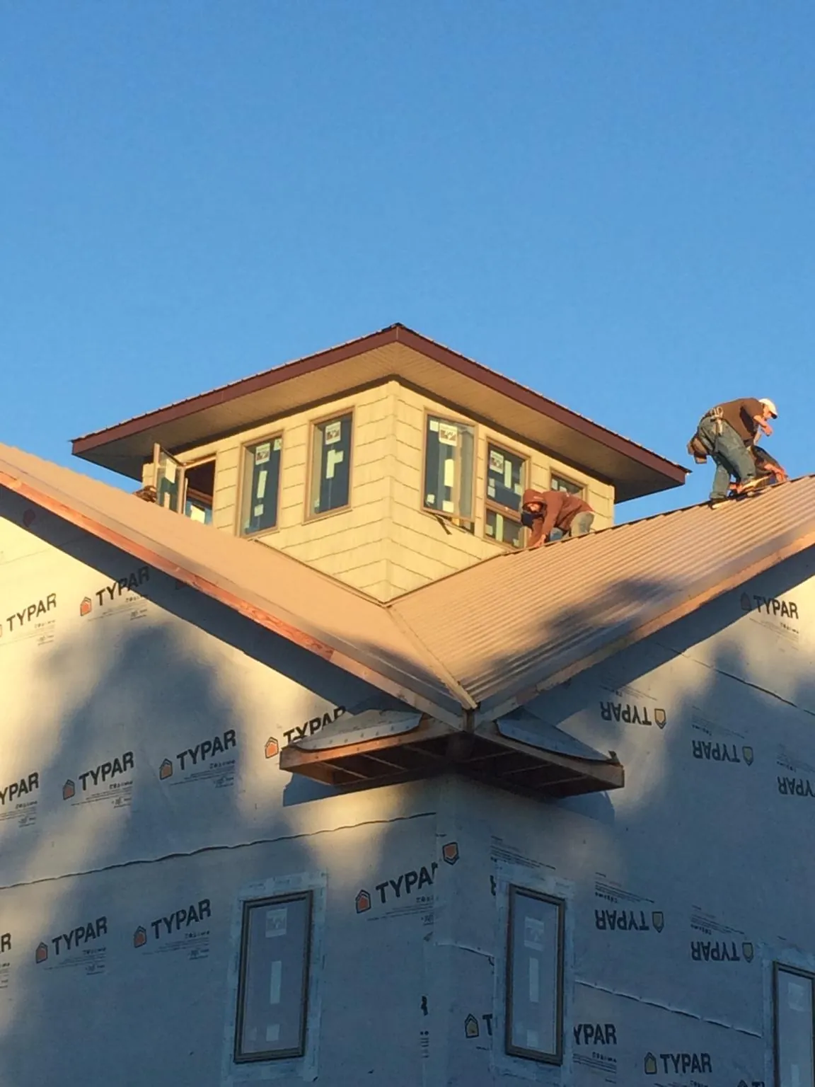 Roofers working around a rooftop cupola on a new metal roof at sunset — Roof Waterproofing in Lake Hopatcong by Roofing Brothers